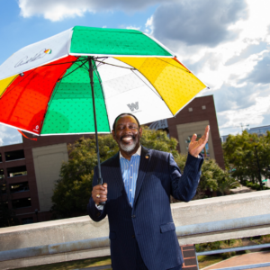 Mayor Demings at the Arnold Palmer Golf Event holding a colorful umbrella.