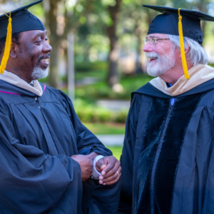 Mayor Demings shaking hands with a fellow alumni at a college ceremony in orange county florida.