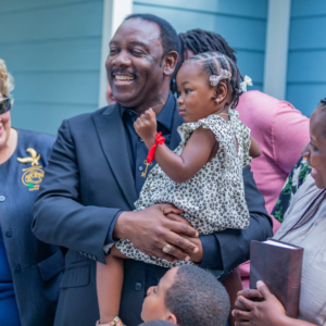 Mayor Demings holding a young girl at a ribbon cutting ceremony in orange county florida.