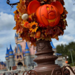 a mickey shaped pumpkin and wreath in front of of the magic kingdom 