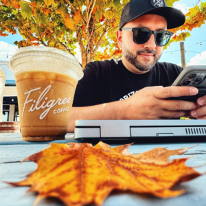 Man sitting outside at a table drinking a coffee from Filigree Coffee