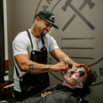 Barber giving a man a shave and facial skin care at barber shop 