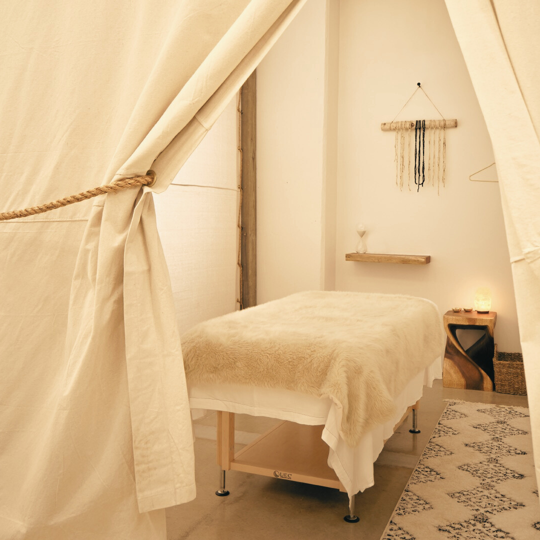 Private massage space with bed, curtains, and calming lighting at The Now 